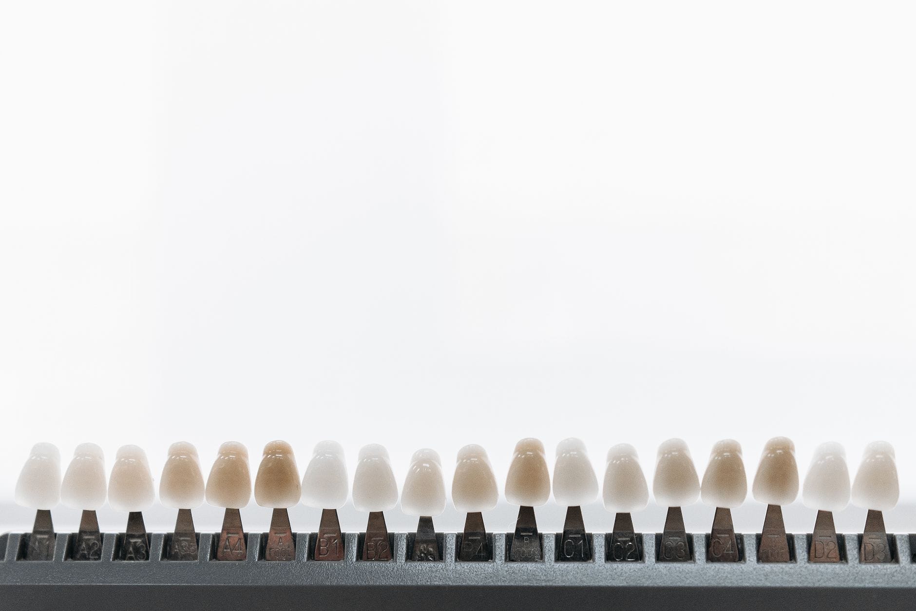 Row of beige to brown color swatches lined up on a metal rack against a pale background.