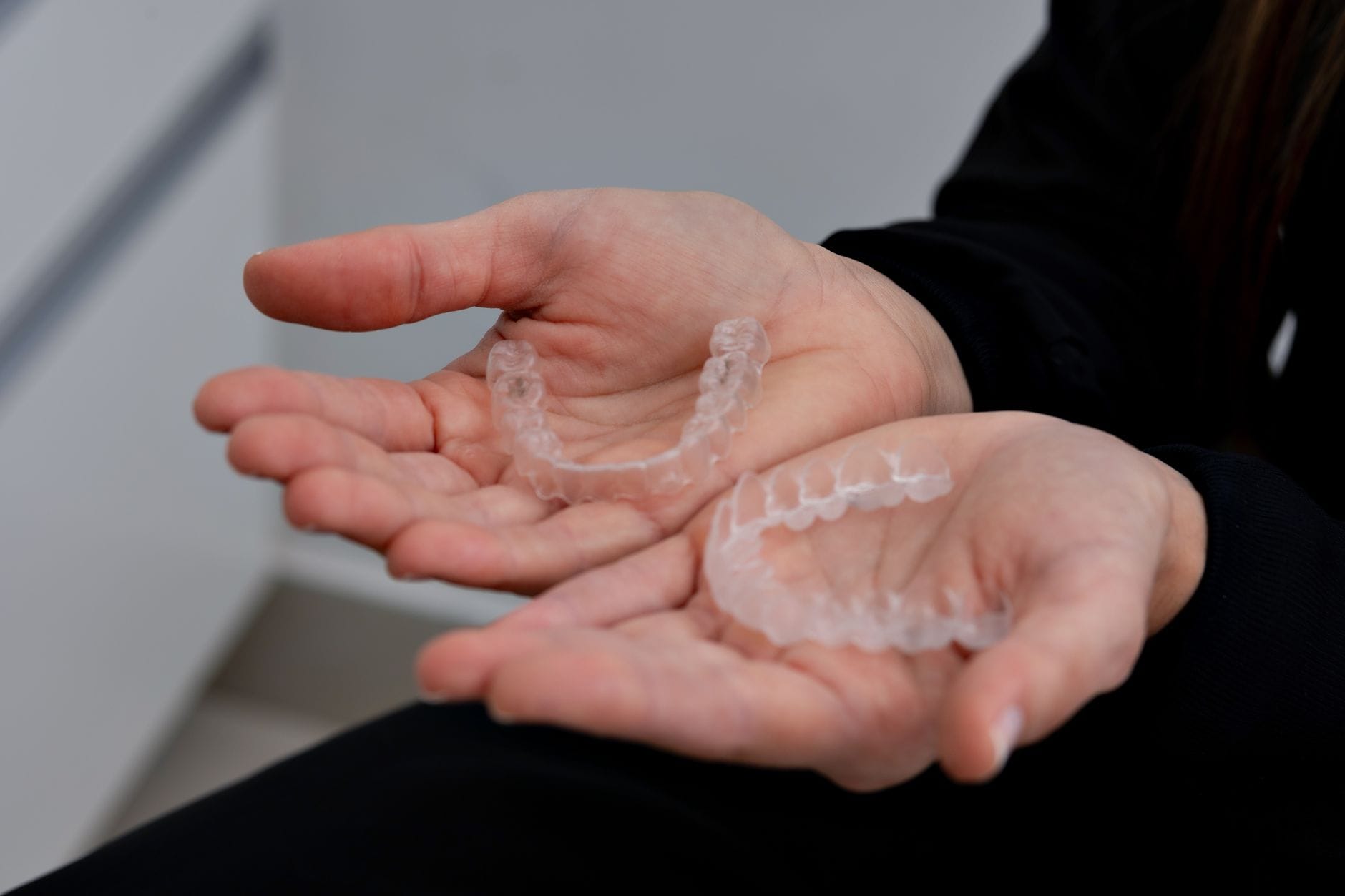 Close-up of hands cupping a clear dental aligner (invisible retainer) in the palm area] , but keep it simple.